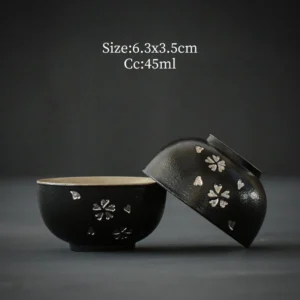 Set of 2 antique Japanese black tea bowls with silver inlaid sakura pattern on wooden tea table