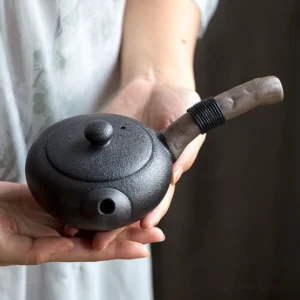 Black matte side handle Japanese porcelain teapot on wooden tea tray