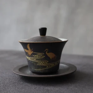 Full view of hand-painted golden black crane porcelain gaiwan with black textured exterior