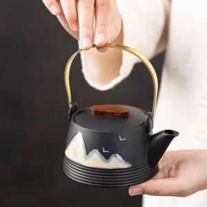 Full view of hand-painted black mountain porcelain teapot with gold metal handle and wooden lid knob