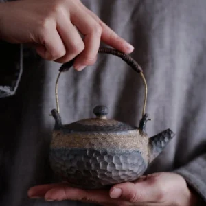 Handcrafted textured Chinese porcelain teapot with bronze metal and rope handle, full product front view