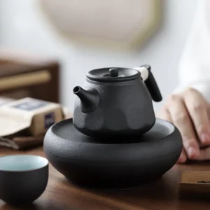 handmade black clay chinese teapot with wrapped cord handle and matching teacup on wooden tray