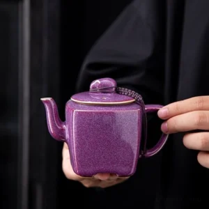 Full side view of handmade square purple ceramic teapot with braided lid cord