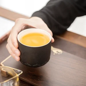 Matte black porcelain tea cup with fu character and lotus relief, 7oz capacity, side view