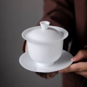 Collection of three sizes pure white porcelain gaiwan tea sets on wood background